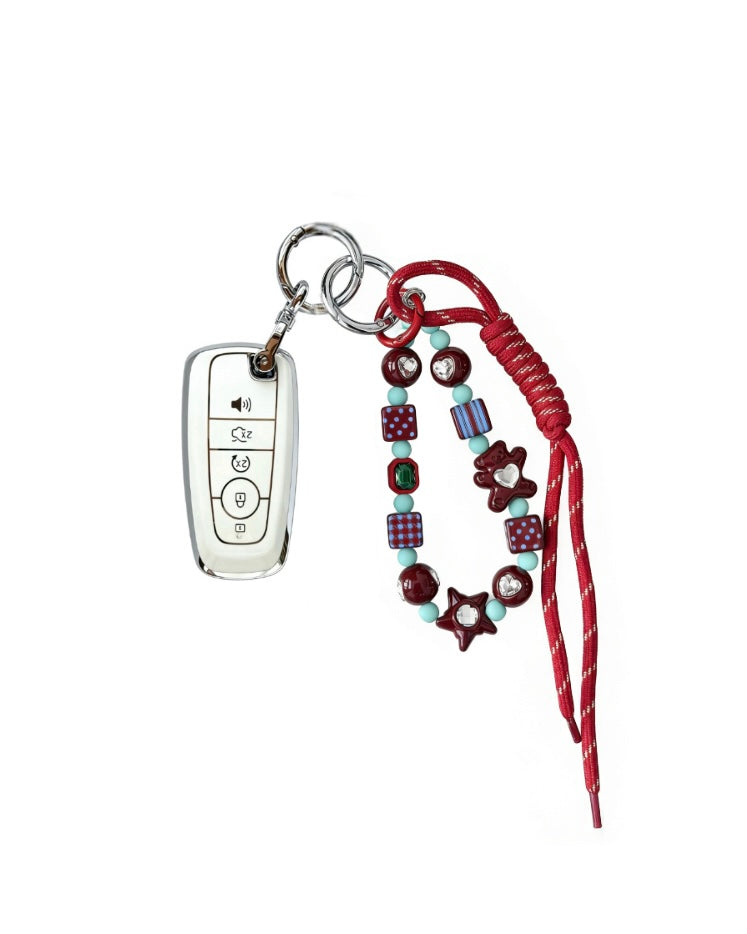 White Ford car key fob cover case with pastel plaid heart design, paired with a handmade beaded keychain featuring cute patterned beads, and a red braided cord on a white background.