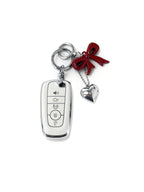White Ford car key fob cover case with red bow keychain with silver heart charm featuring a red “nice day” star design on a white background. Cute aesthetic bag charm and trendy car key accessory for women.
