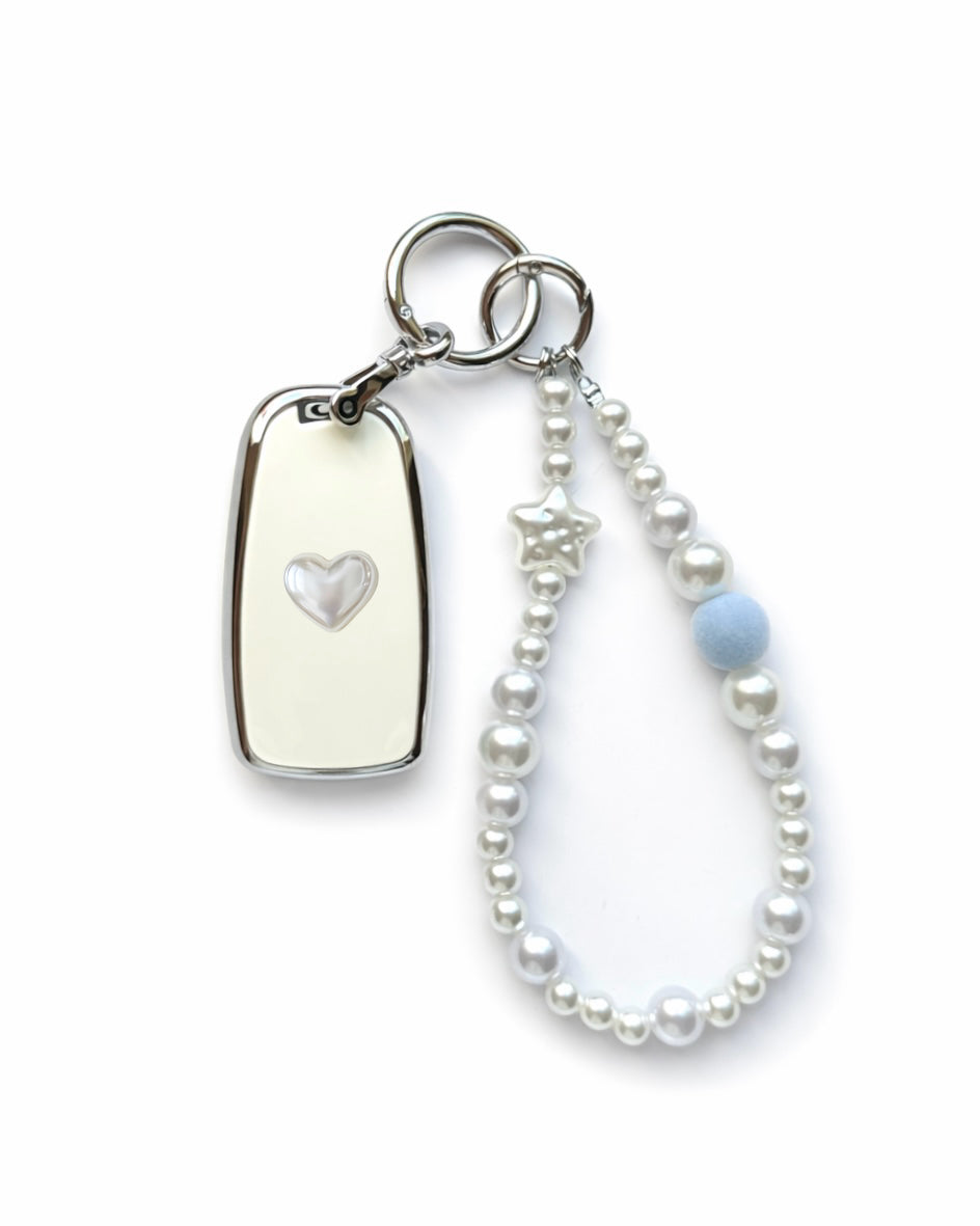 White Chevrolet key fob cover case with a pearl heart on the back, paired with a pearl white beaded wrist strap key chain featuring a blue accent bead and star charm, displayed on a white background.