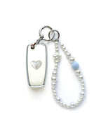 White Ford key fob cover case with a pearl heart on the back, paired with a pearl white beaded wrist strap key chain featuring a blue accent bead and star charm, displayed on a white background.